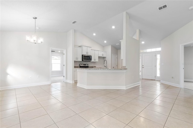 kitchen with white cabinets, light tile patterned floors, light stone counters, kitchen peninsula, and stainless steel appliances