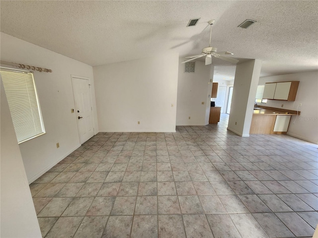 unfurnished living room with ceiling fan and a textured ceiling