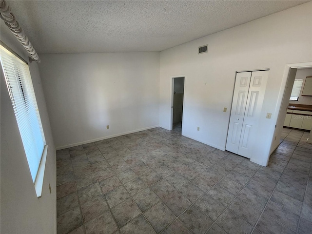 unfurnished bedroom featuring visible vents, multiple windows, a textured ceiling, and baseboards