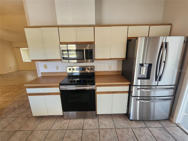 kitchen with backsplash, cream cabinetry, light tile patterned floors, and appliances with stainless steel finishes