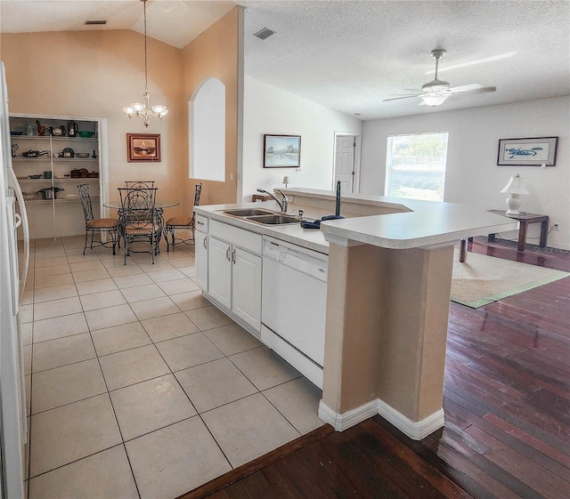 kitchen featuring lofted ceiling, visible vents, a sink, white appliances, and ceiling fan with notable chandelier