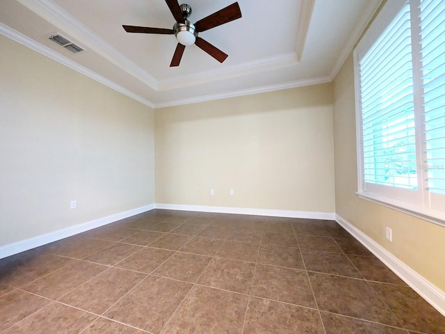 tiled spare room featuring ceiling fan, a raised ceiling, and ornamental molding