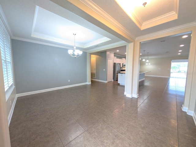 unfurnished room with a raised ceiling, crown molding, and a notable chandelier