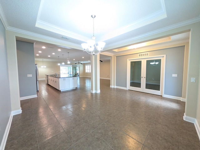 interior space featuring a tray ceiling, french doors, a chandelier, and ornamental molding