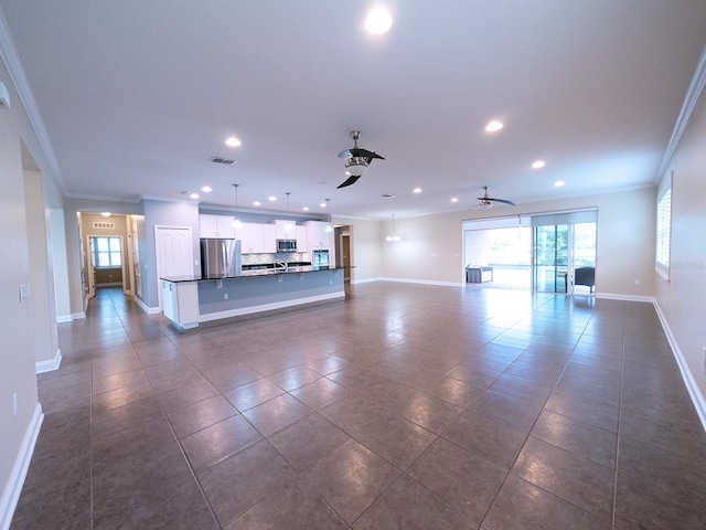 unfurnished living room featuring ceiling fan, dark tile patterned floors, and crown molding