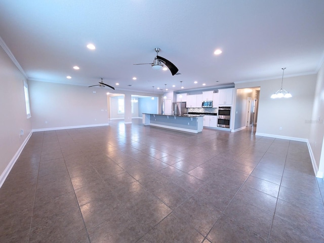 unfurnished living room with ceiling fan with notable chandelier, ornamental molding, and a wealth of natural light