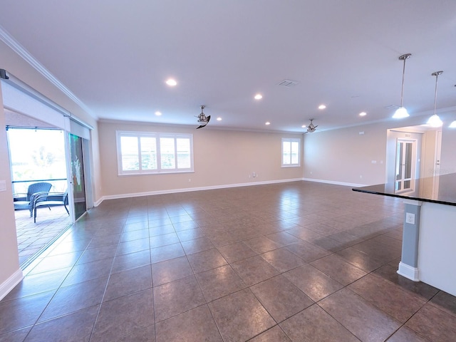 unfurnished living room featuring dark tile patterned floors, ceiling fan, and crown molding