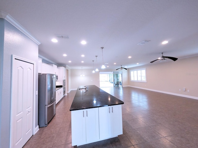 kitchen with white cabinets, pendant lighting, stainless steel appliances, and a kitchen island with sink