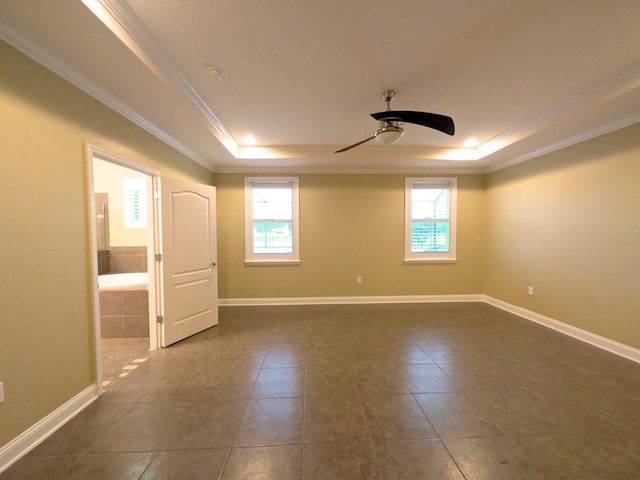 empty room with a raised ceiling, ceiling fan, crown molding, and dark tile patterned flooring