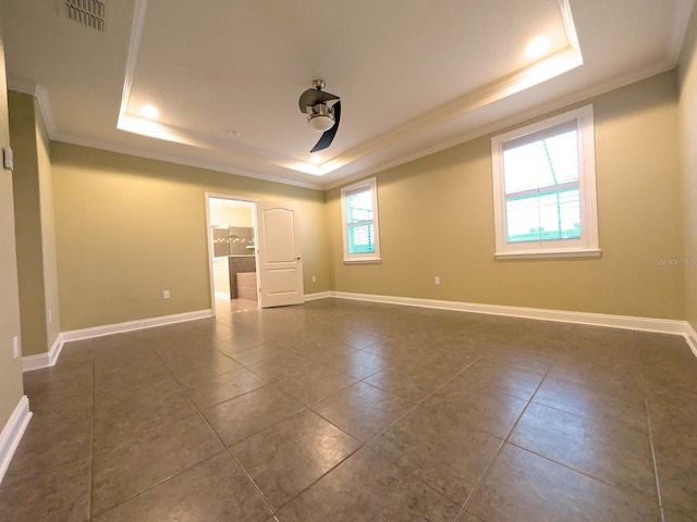 unfurnished room with a tray ceiling, crown molding, ceiling fan, and dark tile patterned flooring