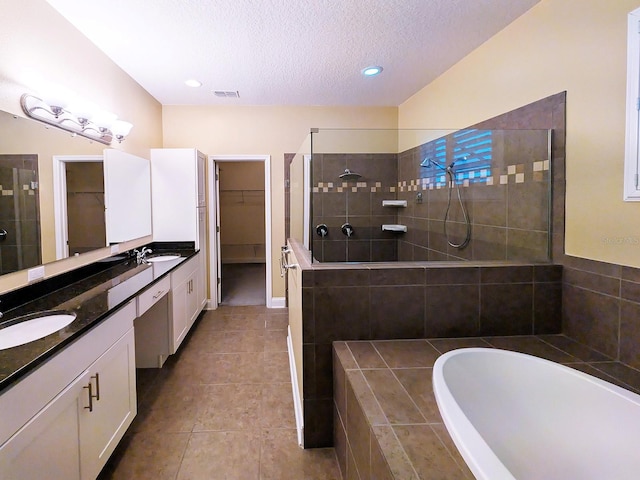 bathroom with plus walk in shower, tile patterned flooring, vanity, and a textured ceiling