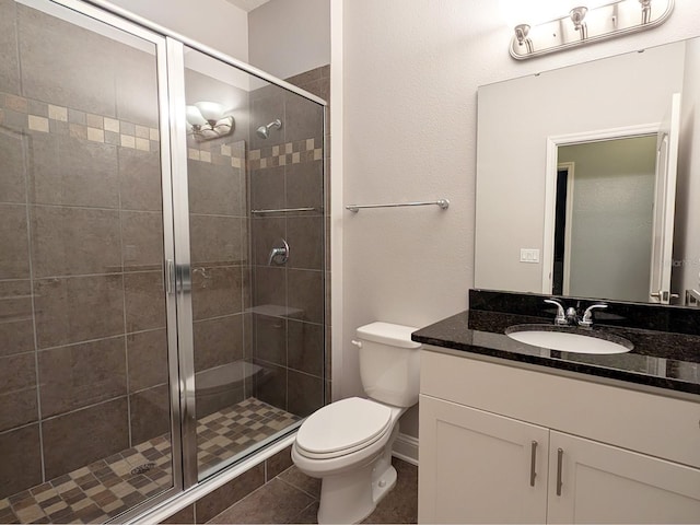 bathroom featuring tile patterned floors, vanity, toilet, and walk in shower