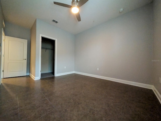 unfurnished bedroom featuring ceiling fan, a closet, and dark tile patterned flooring