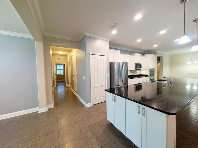 kitchen with stainless steel appliances, sink, pendant lighting, white cabinetry, and an island with sink