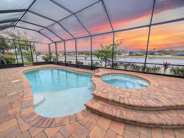 pool at dusk featuring glass enclosure and an in ground hot tub