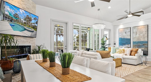 sunroom with vaulted ceiling, ceiling fan with notable chandelier, and a fireplace