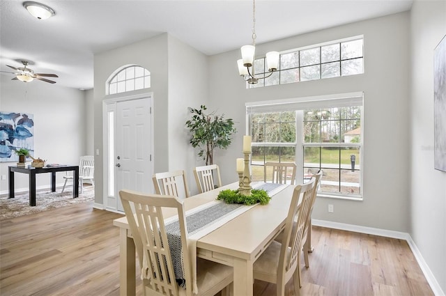 dining space with ceiling fan with notable chandelier and light wood-type flooring