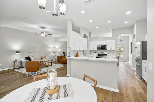 dining room with light hardwood / wood-style floors and ceiling fan with notable chandelier