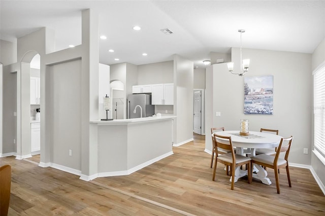 dining room with light wood-type flooring, lofted ceiling, and a notable chandelier