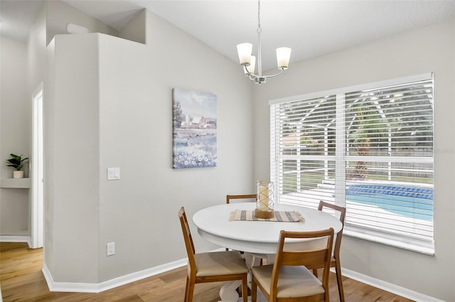 dining area with light hardwood / wood-style floors, lofted ceiling, and a notable chandelier