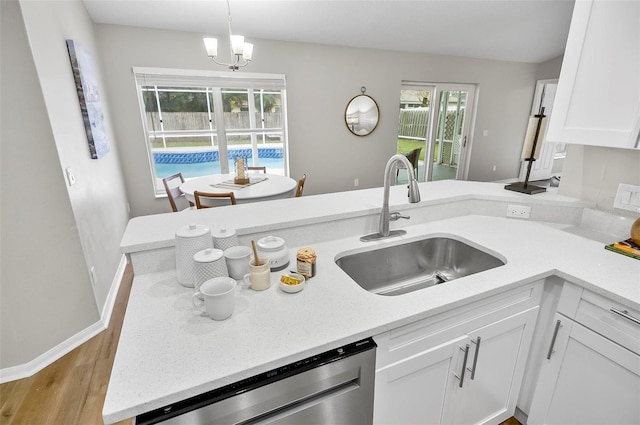 kitchen featuring pendant lighting, dishwasher, an inviting chandelier, white cabinets, and sink