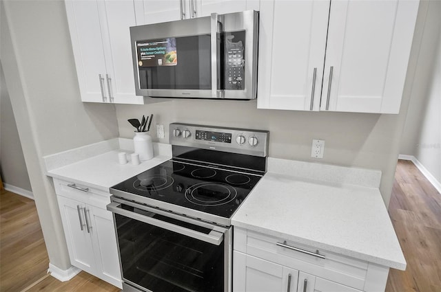 kitchen featuring light stone countertops, white cabinetry, stainless steel appliances, and light hardwood / wood-style floors