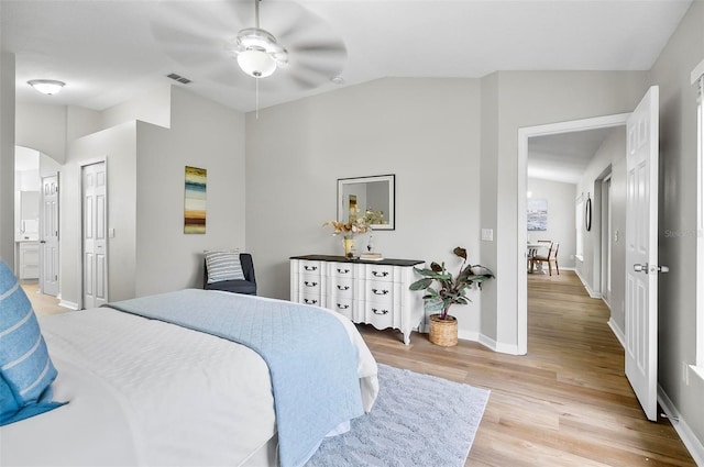 bedroom featuring light wood-type flooring, vaulted ceiling, ceiling fan, and connected bathroom