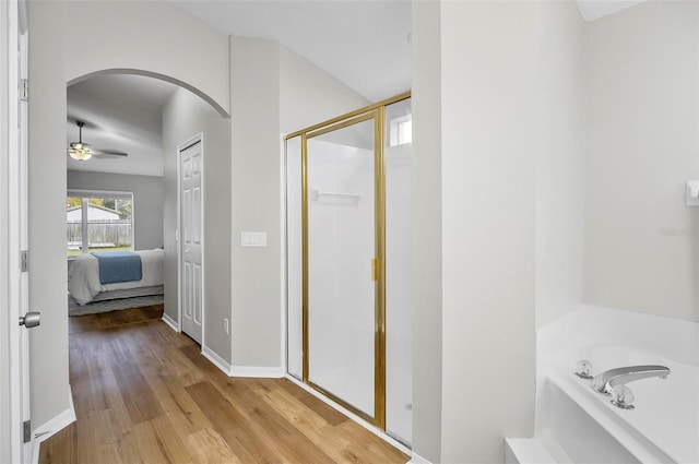 bathroom featuring ceiling fan, wood-type flooring, and shower with separate bathtub