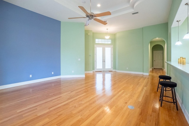 unfurnished room with ceiling fan, french doors, a towering ceiling, and light wood-type flooring