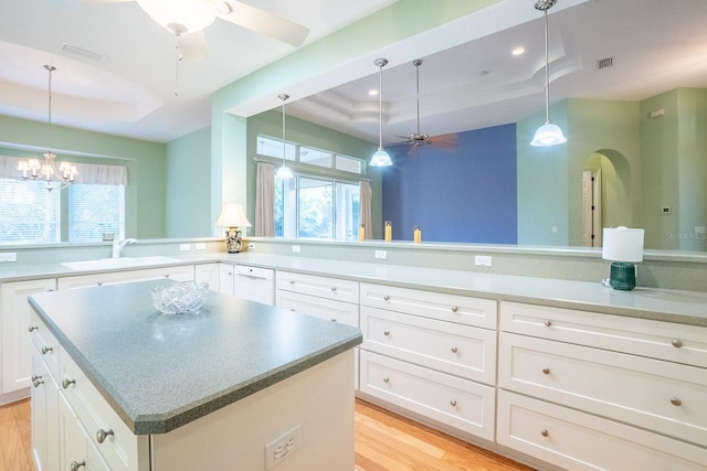 kitchen with white cabinets, sink, and a tray ceiling