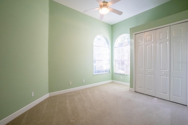 unfurnished bedroom with light carpet, a closet, and ceiling fan