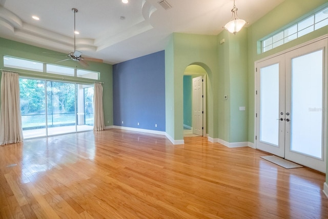 spare room featuring french doors, light wood-type flooring, a raised ceiling, and ceiling fan