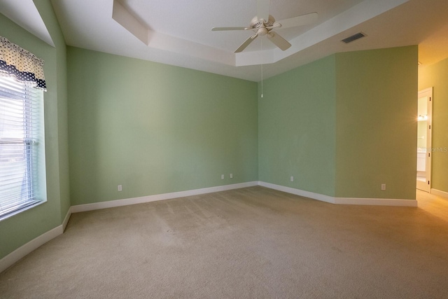 carpeted spare room featuring a tray ceiling and ceiling fan