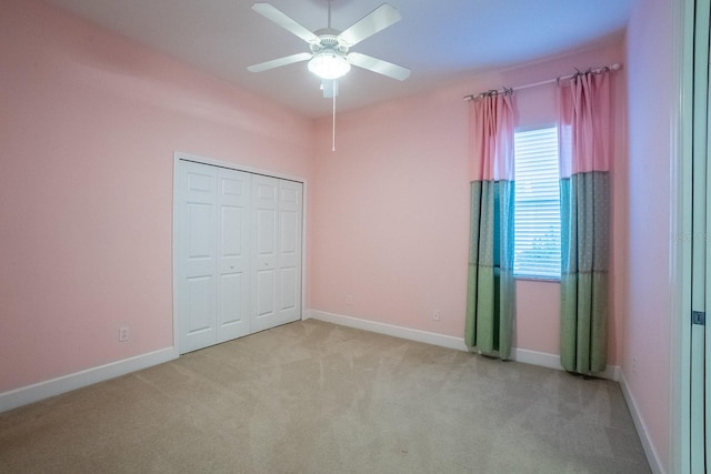 unfurnished bedroom featuring light carpet, a closet, and ceiling fan