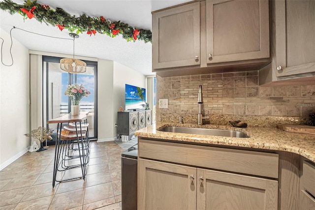 kitchen featuring sink, light stone counters, backsplash, pendant lighting, and light tile patterned flooring