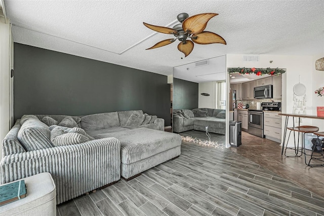 living room with ceiling fan and a textured ceiling