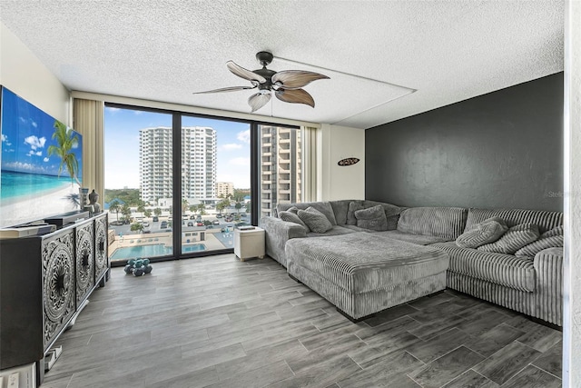 living room featuring hardwood / wood-style floors, ceiling fan, expansive windows, and a textured ceiling