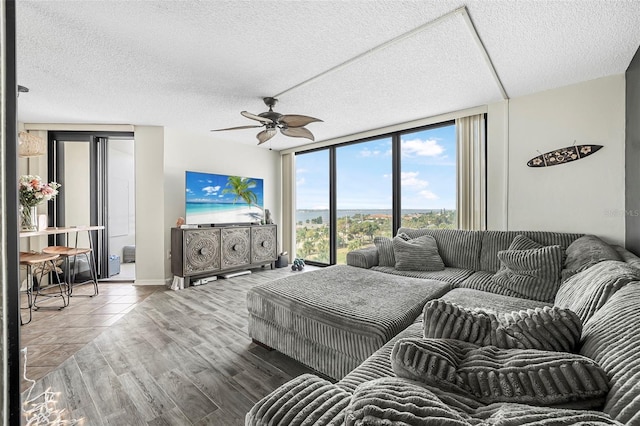 living room featuring ceiling fan, floor to ceiling windows, wood-type flooring, and a textured ceiling