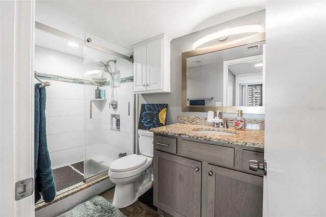 bathroom featuring hardwood / wood-style floors, vanity, toilet, and a shower with door