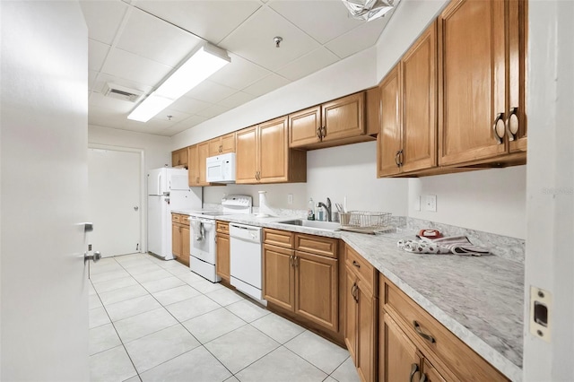 kitchen featuring white appliances, sink, and light tile patterned floors