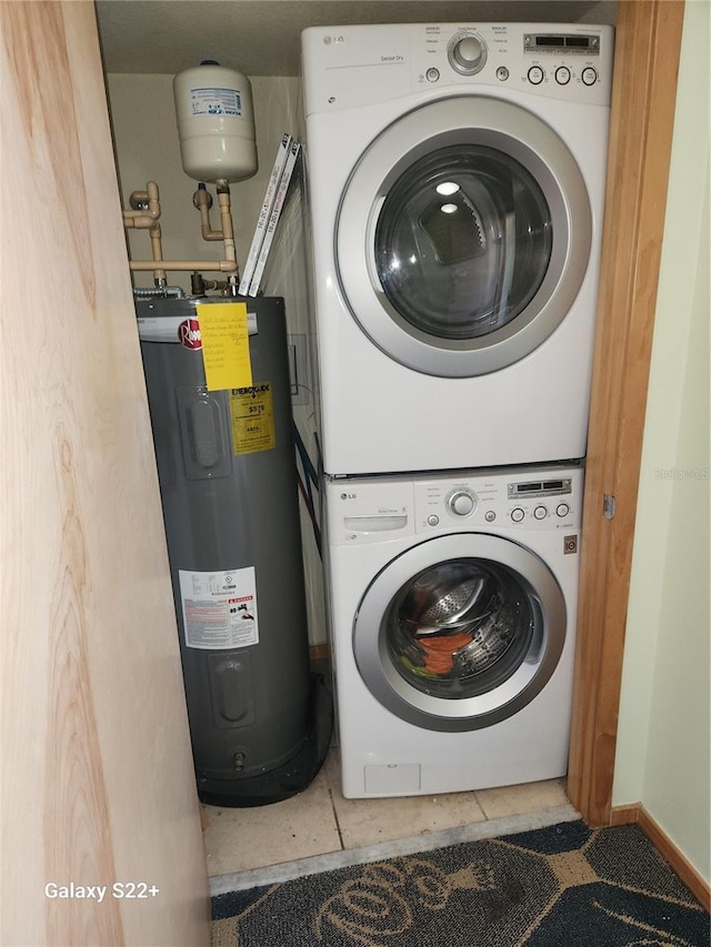 laundry room with tile patterned flooring, electric water heater, and stacked washing maching and dryer