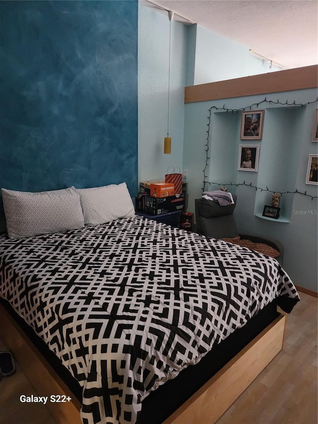 bedroom featuring a textured ceiling, hardwood / wood-style flooring, and vaulted ceiling