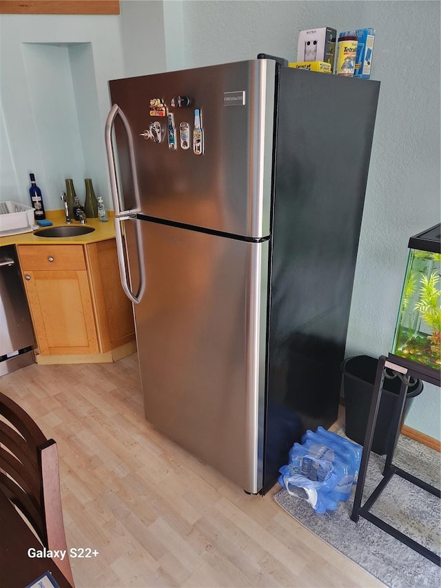 kitchen with dishwasher, stainless steel fridge, light hardwood / wood-style floors, and sink