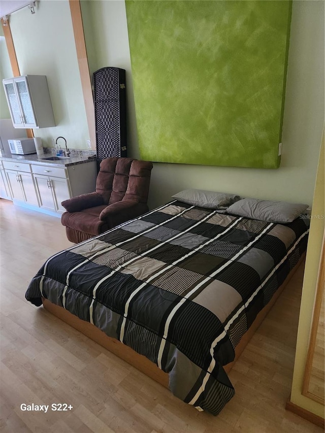 bedroom featuring light wood-type flooring and sink