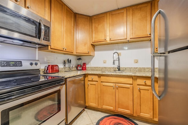 kitchen featuring light stone countertops, appliances with stainless steel finishes, light tile patterned floors, and sink