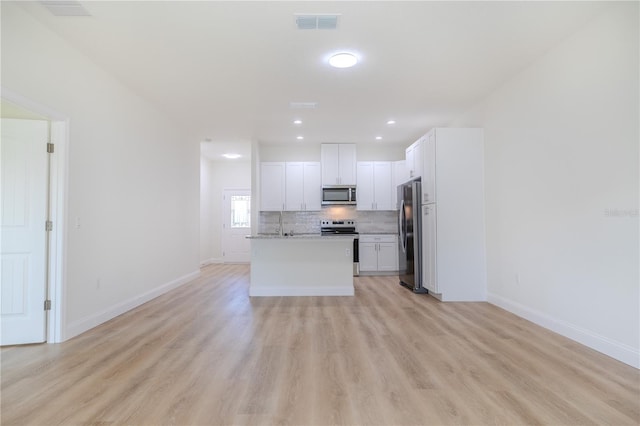 kitchen with backsplash, stainless steel appliances, light hardwood / wood-style floors, white cabinetry, and an island with sink