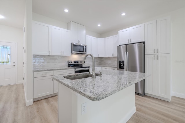 kitchen with sink, white cabinets, stainless steel appliances, and a center island with sink