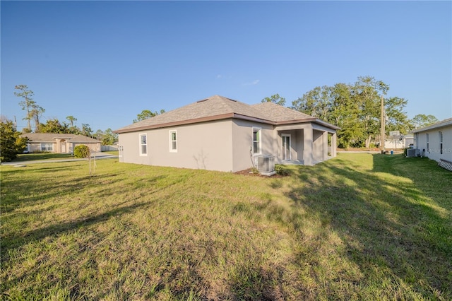 rear view of property with central AC unit and a yard