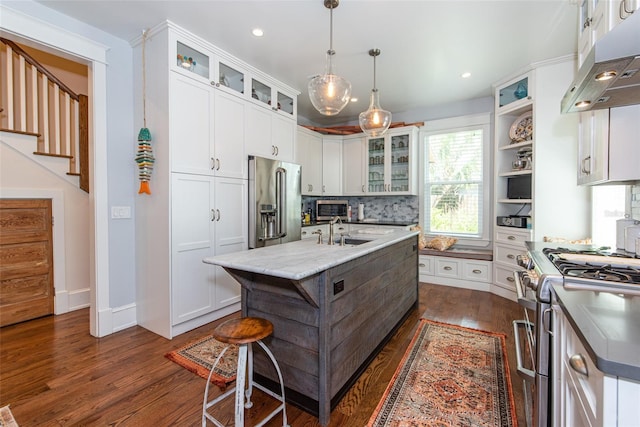 kitchen featuring white cabinets, a center island with sink, high quality appliances, and exhaust hood