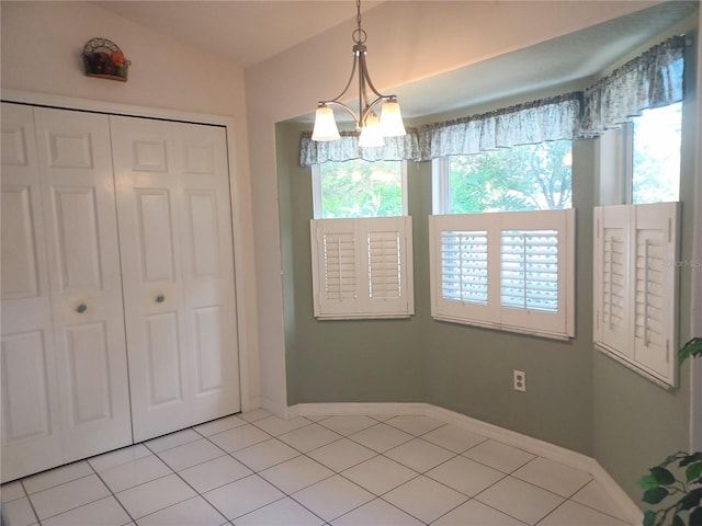 unfurnished bedroom featuring a notable chandelier, a closet, light tile patterned floors, and multiple windows